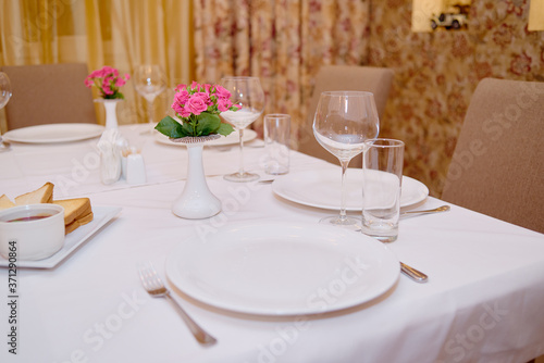 Table set with sparkling wineglasses, plates with serviette and cutlery on table, copy space. Place setting at wedding reception. Table served for wedding banquet in restaurant
