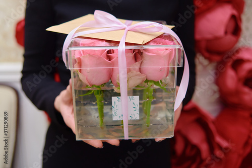 Woman holding in hands pink rose flowers in box, copy space. Greeting card for Womens Day, Mothers Day, Valentines Day, wedding, birthday
