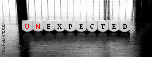 Tableau sur toile dices with letters forming word expected or unexpected on a black and white