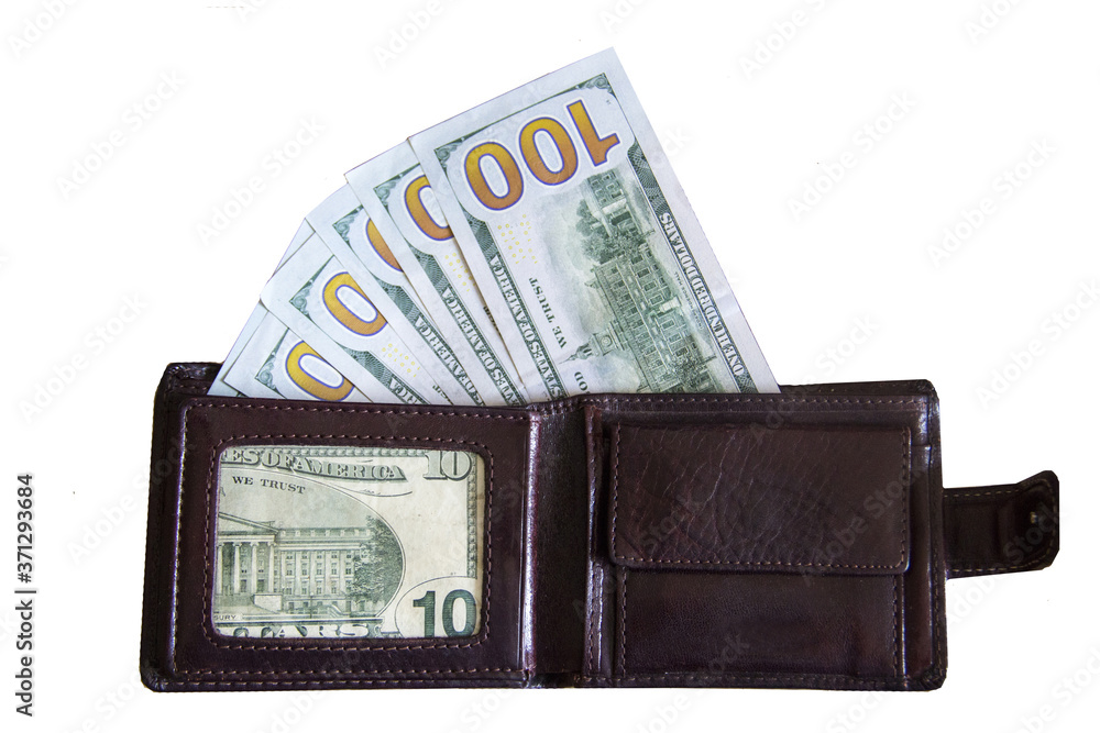 Dollars peek out of the wallet while it lies on a wooden table. A wallet with money lies on the table in the office. Dollars peek out of the wallet while it lies on a wooden table. A wallet with money lies on the table in the office.