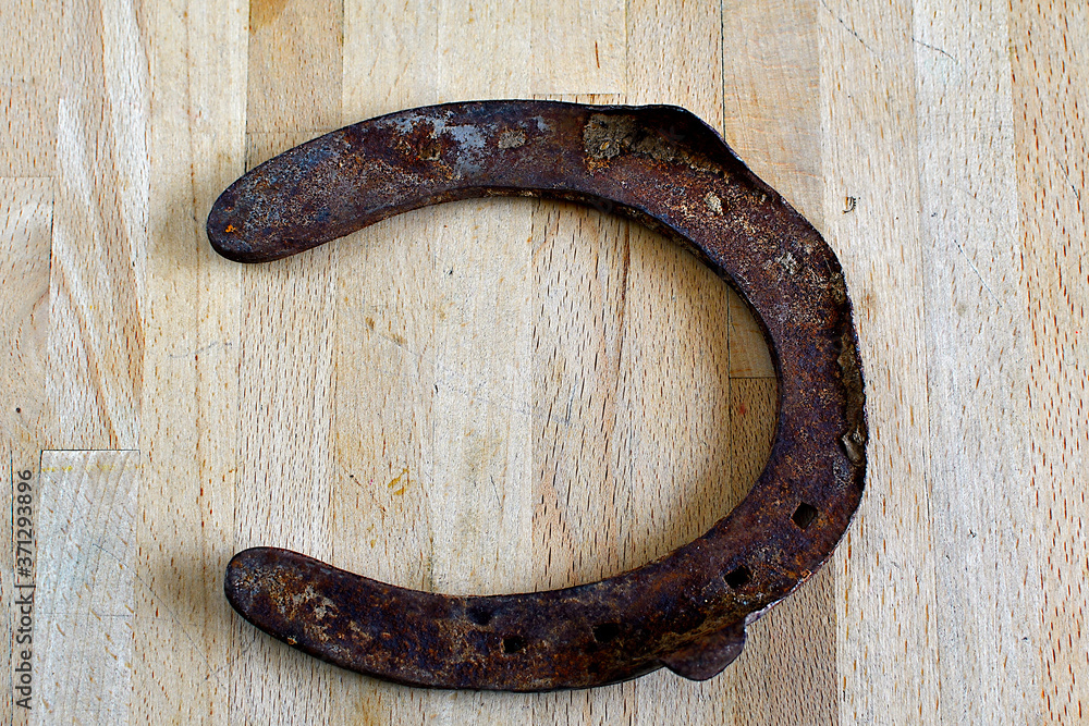 Old used and rusty horseshoe thrown on a wooden plank Old used and rusty horseshoe thrown on a wooden plank