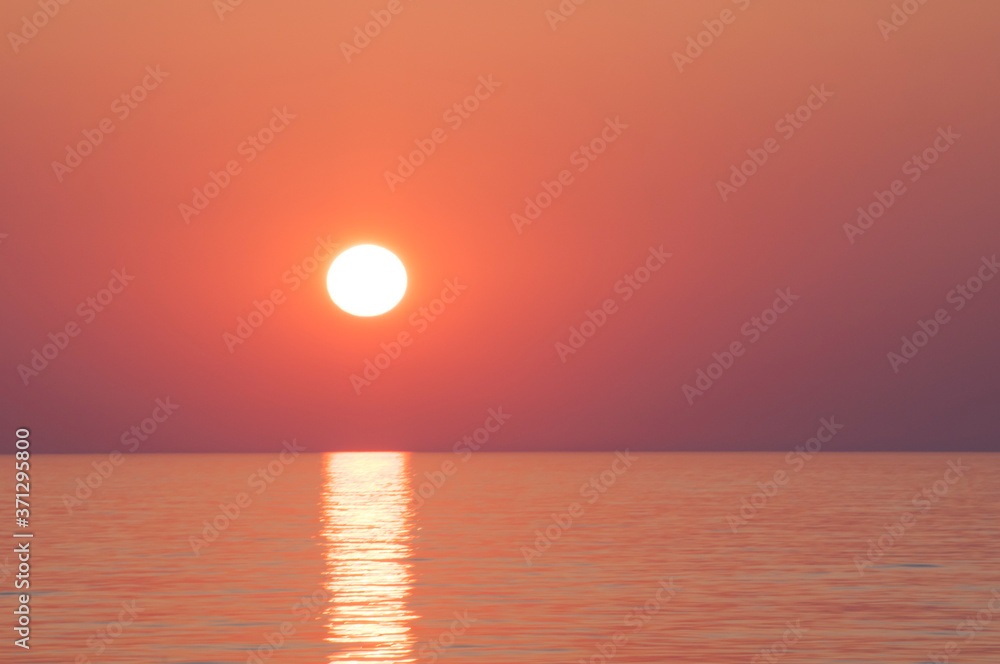 Zbliżenie na zachód słońca nad spokojną taflą morza - prosta linia horyzontu - wyraźne kolory