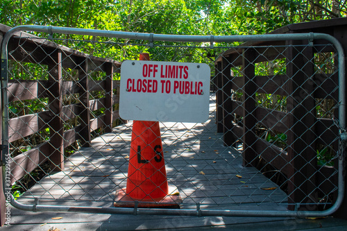 A Boardwalk With a Fenced Off Section With a Sign Stating That It's Off Limits and Closed to the Public photo