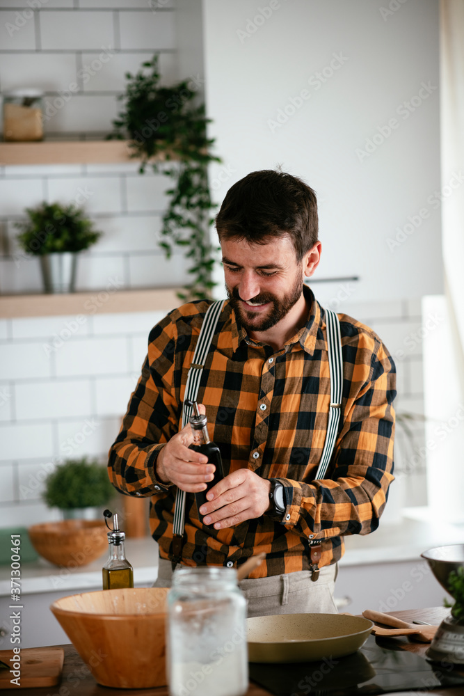 Portrait of handsome man in kitchen. Young man preparing delicious food. Portrait of handsome man in kitchen. Young man preparing delicious food.