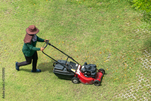 woman worker working pushing grass trimming with a lawnmower