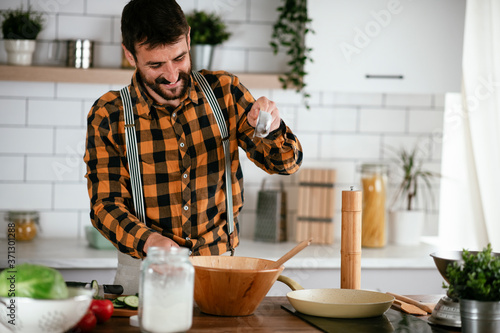 Portrait of handsome man in kitchen. Young man preparing delicious food.