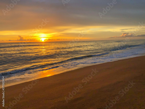 Bright sunset over the ocean with a golden sky and reflections on water