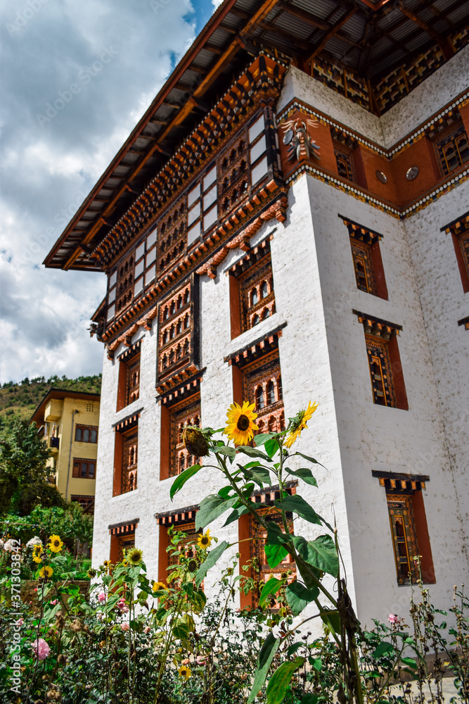 A traditional bhutanese building surrounded by sunflowers, in Thimphu, capital of Bhutan.