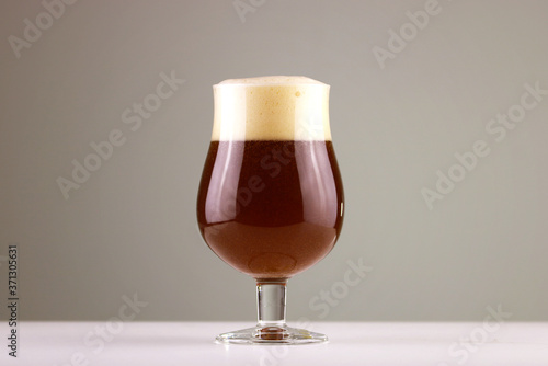 Glass of deep red craft beer with nice foam