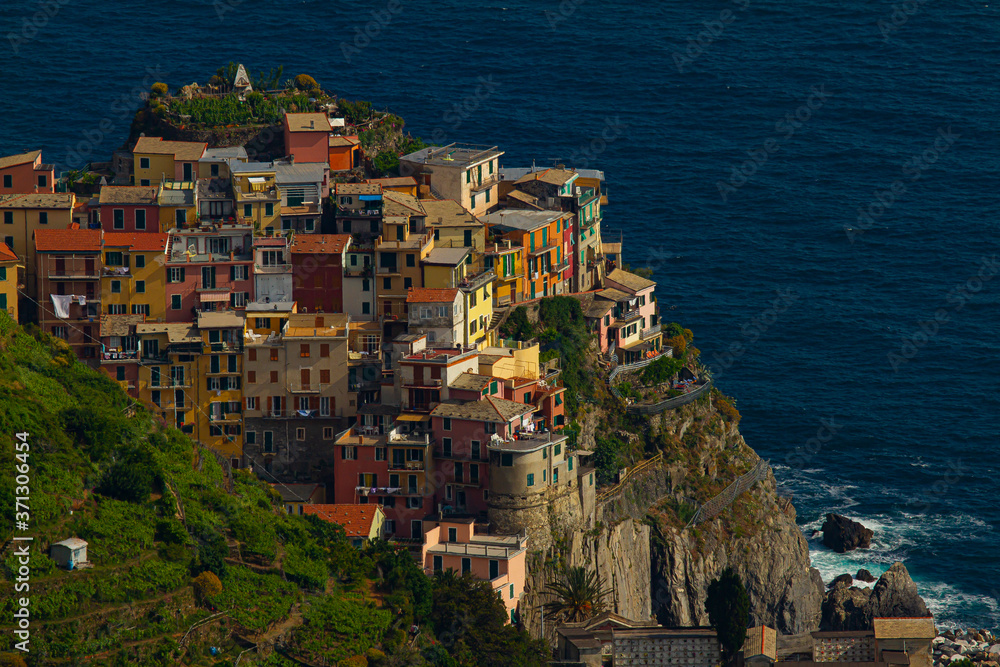 Close up image of a scenic and isolated town in Cinque Terre which is located on a rocky surface at the foothills of  steep cliffs and by the sea. Houses are seen as clusters on top of the boulder.