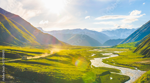 Truck is driving through truso valley with terek river on the right side surounded by KAzbegi mountains. Scenic georgian highlands during the sunset.