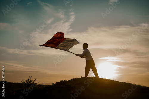 Little Boy Waving Red and White Indonesian Flag in sunset nature