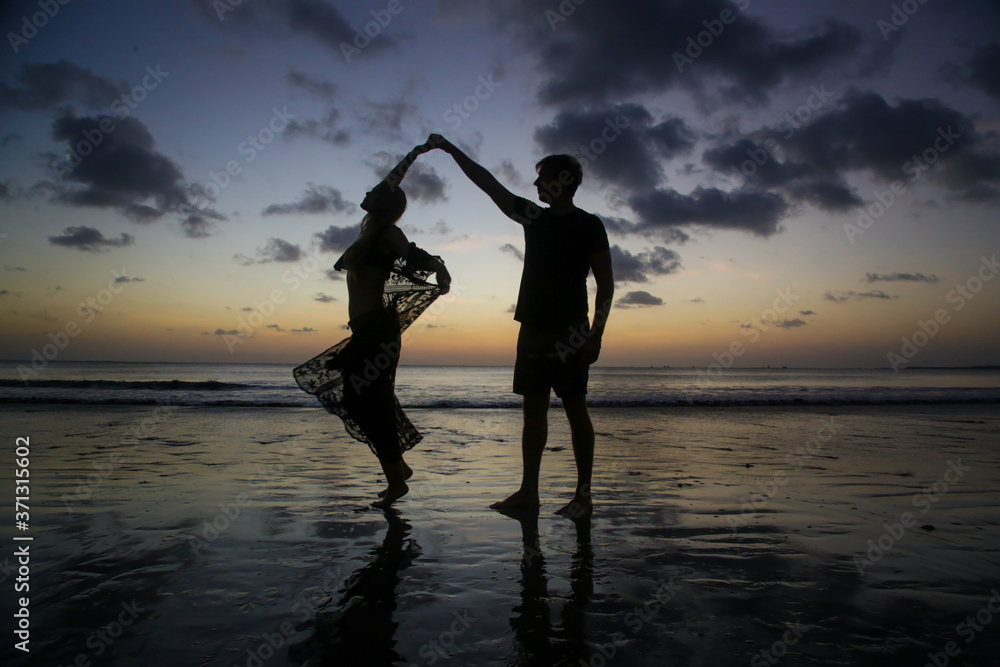 Silhouette of a young couple in love on a beach during the sunset time.