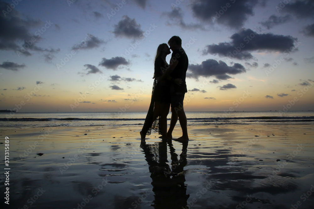 Silhouette of a young couple in love on a beach during the sunset time.