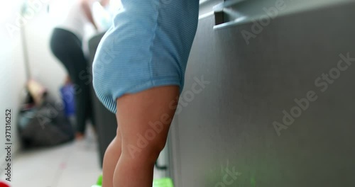 Baby toddler at kitchen sink on tiptoes helping with houseold photo