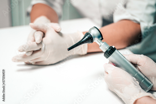 Close-up otoscope checking ears by a doctor in a laboratory. hands of female laboratory assistant and veterinarian doctor. Diagnostic equipment for otitis media and ear diseases.