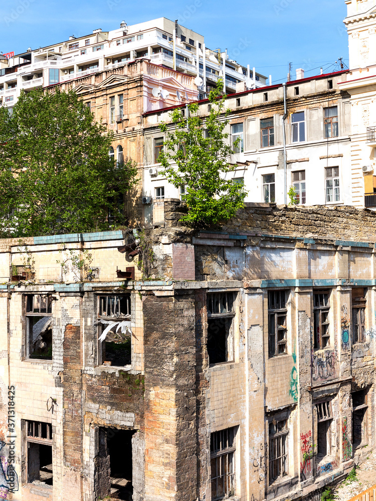 Panoramic view of the street with decaying houses in a poor neighborhood. Ruined building after a natural disaster. Provide shelter for homeless people and drug addicts.
