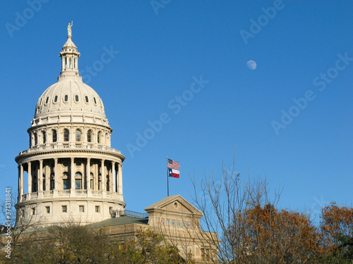 the Capitol of Texas with a three quarter moon and a stiff breeze blowing on the US and State flags photo