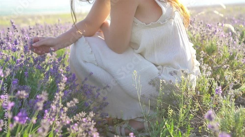 Woman in lavender flowers field at sunset in white dress and hat