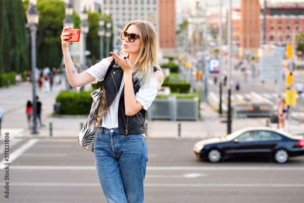 Pretty tourist blonde woman making selfie on the street, stylish casual outfit and sunglasses, traveling in Europe.