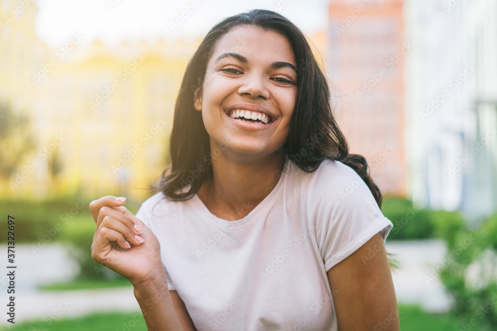Outdoor portrait of beautiful dark skinned girl with perfect smile enjoying sunny summer day-off Outdoor portrait of beautiful dark skinned girl with perfect smile enjoying sunny summer day-off