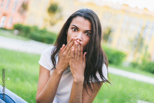 Young dark skinned woman covering her mouth with hands with shocked face expression eyes wide open
