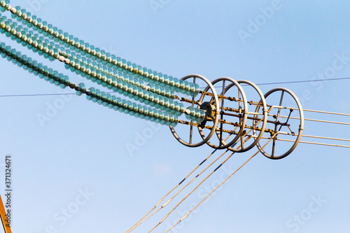 Power lines. High voltage power pylons against blue sky and sun rays