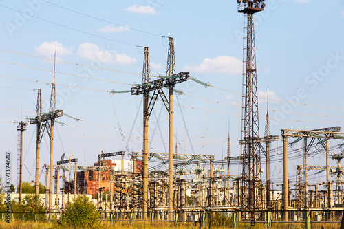 Power lines. High voltage power pylons against blue sky and sun rays