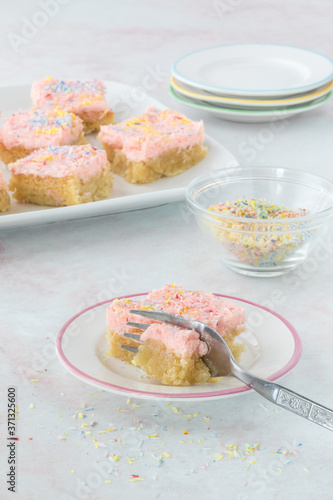 Keto sugar cookie bar garnished with coconut sprinkles with a fork cutting through for eating. photo