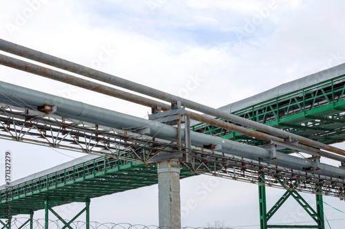 Fragment Metal grain elevator in agricultural zone. Agricultural Silos. Building Exterior. Storage and drying of grains, wheat, corn, soy, sunflower on background of cloudy sky. Agriculture.