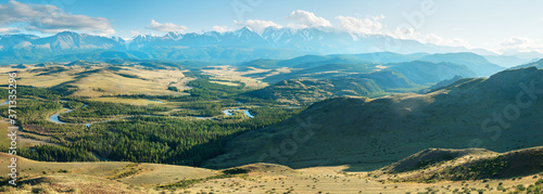 Scenic panoramic view, Altai mountains. Snow-capped peaks in blue haze, evening light. 