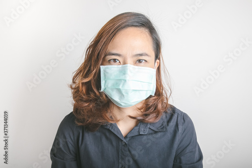 Close up face shot of pretty asian woman model with age of 30s who is wearing medical mask to protect virus and influenza epidemic shows strong and beauty eye contact on white background in studio