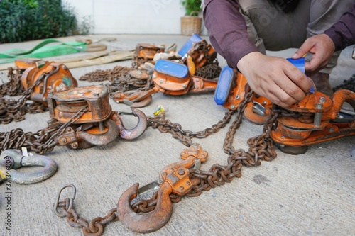 Orange color Industrial hook with chains or chain hoist on concrete floor to wait for the Monthly inspection which is a condition of use of the industrial factory, Department of oil and gas production