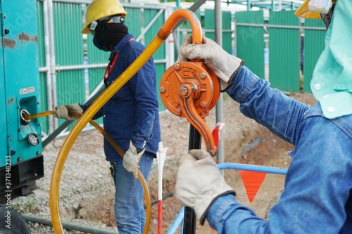 Workers use rotate the hand pump for sucking oil to fuel up the electricity generator. photo