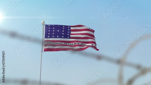 Flying flag of Bikini Atoll  behind barbed wire fence.  photo