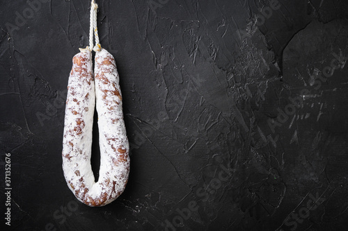 Fuet salami wurst on black textured background with copy space