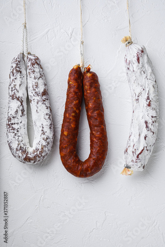 Traditional dry cured sausages meat hanging on white background