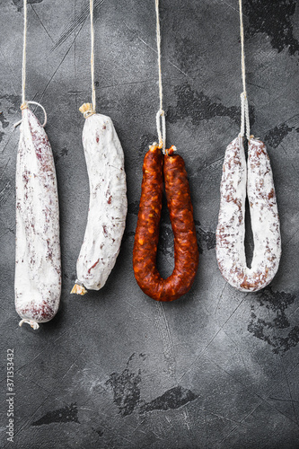 Spanish dry salami from a rack at market on grey background