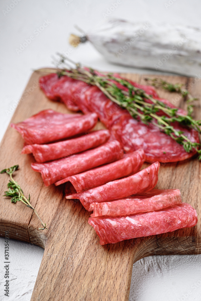Salchichon whole and sliced cuts, spanish sausage on white textured background