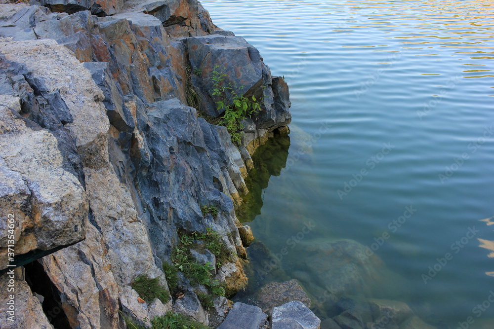 Close-up of granite rock in the water. Natural stone wall background. Selective focus