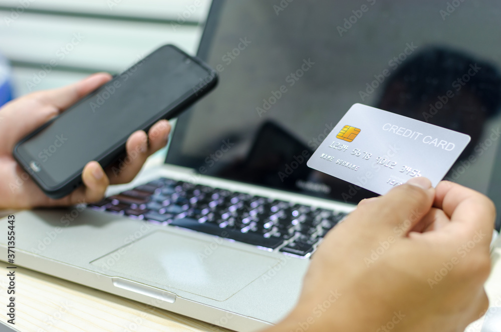 Man Shopping Online Using Laptop With Credit Card.Hands holding credit card and smartphone. Man Shopping Online Using Laptop With Credit Card.Hands holding credit card and smartphone.