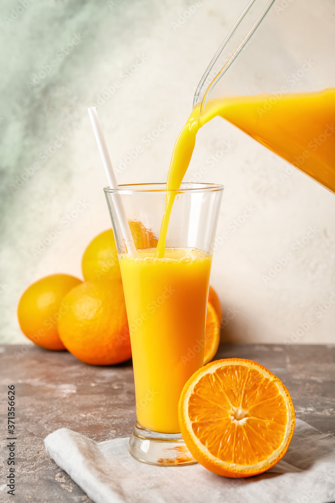 Pouring of fresh orange juice in glass on table Pouring of fresh orange juice in glass on table