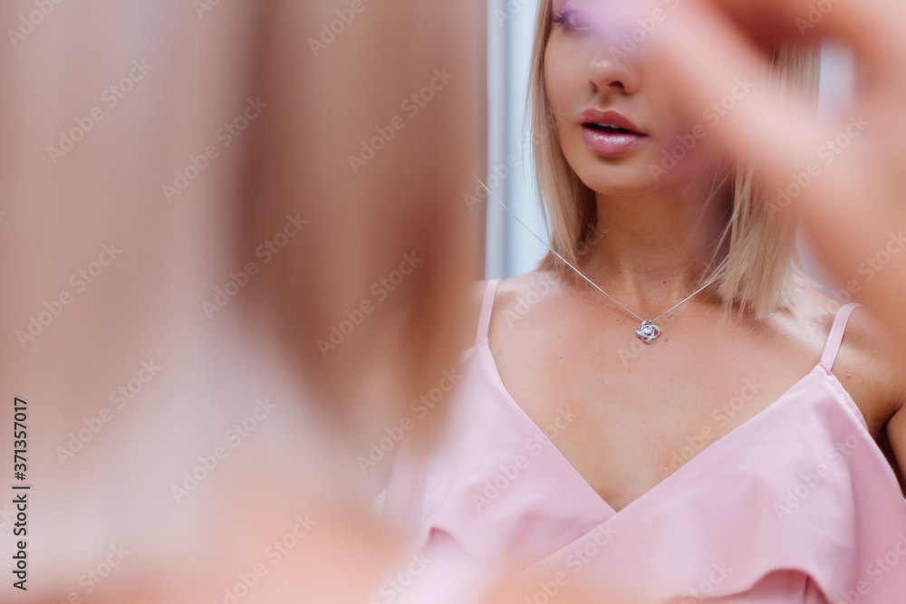 Outdoor portrait of woman in pink romantic dress wearing necklace 