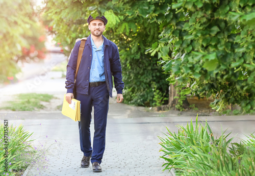 Handsome young postman with letters outdoors © Pixel-Shot