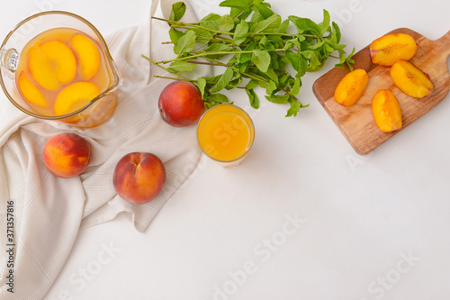 Jug and glass of tasty peach juice on white background