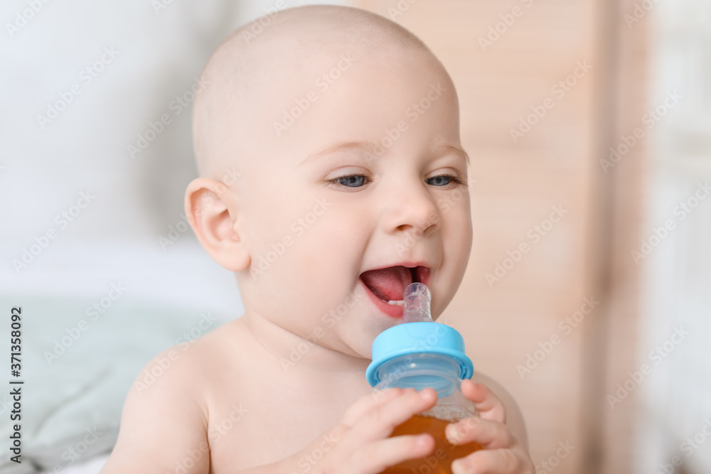 Cute little baby drinking juice from bottle at home Cute little baby drinking juice from bottle at home