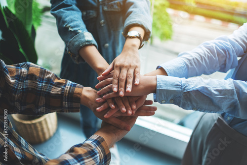 Closeup image of business team standing and joining their hands together in office