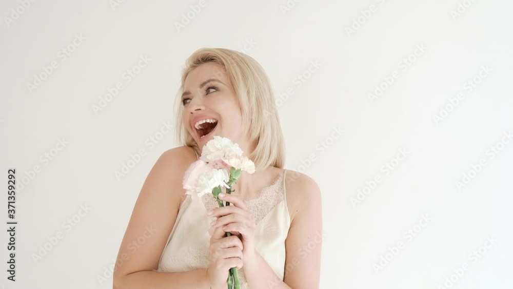 portrait of a young attractive gentle blonde in a white dress on a white background, who holds a bouquet of white flowers in her hands, shows emotions portrait of a young attractive gentle blonde in a white dress on a white background, who holds a bouquet of white flowers in her hands, shows emotions