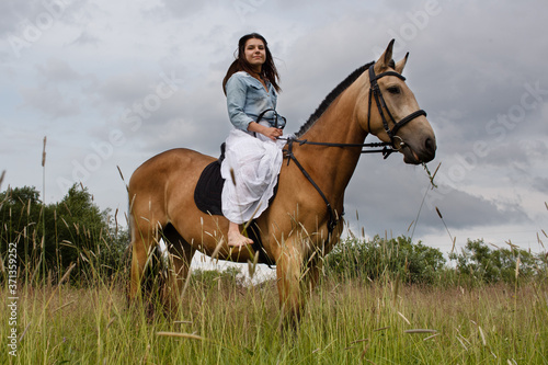 Young cow girl walking horse in green field. People and animal portrait. Horseback riding view. Active weekend © Эльвира Кулешова