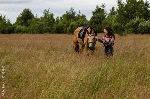 Young cow girl walking horse in green field. People and animal portrait. Horseback riding view. Active weekend © Эльвира Кулешова